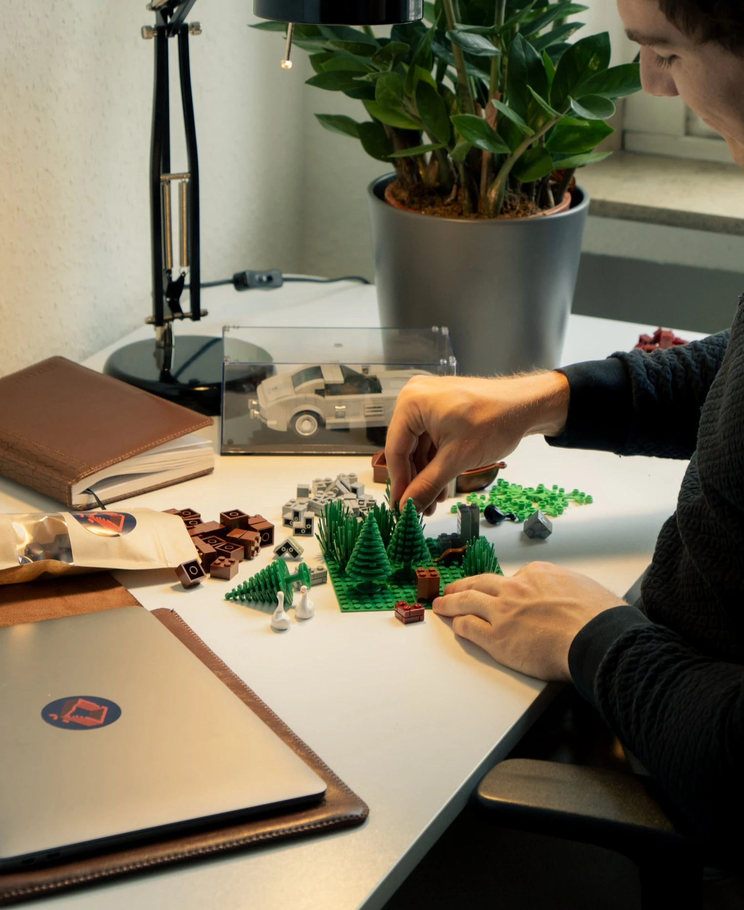 Ein Tisch, auf dem eine Person mit vielen Penny Bricks Klemmbausteinen kreativ etwas zusammenbaut. Im Hintergrund steht ein Penny Bricks Set